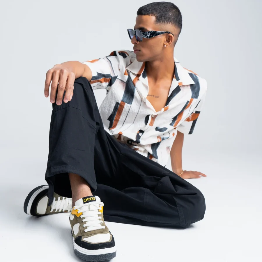 Model wearing Taxi CHNKS sneakers with white shirt and black trousers – men’s yellow and green sneakers for streetwear style